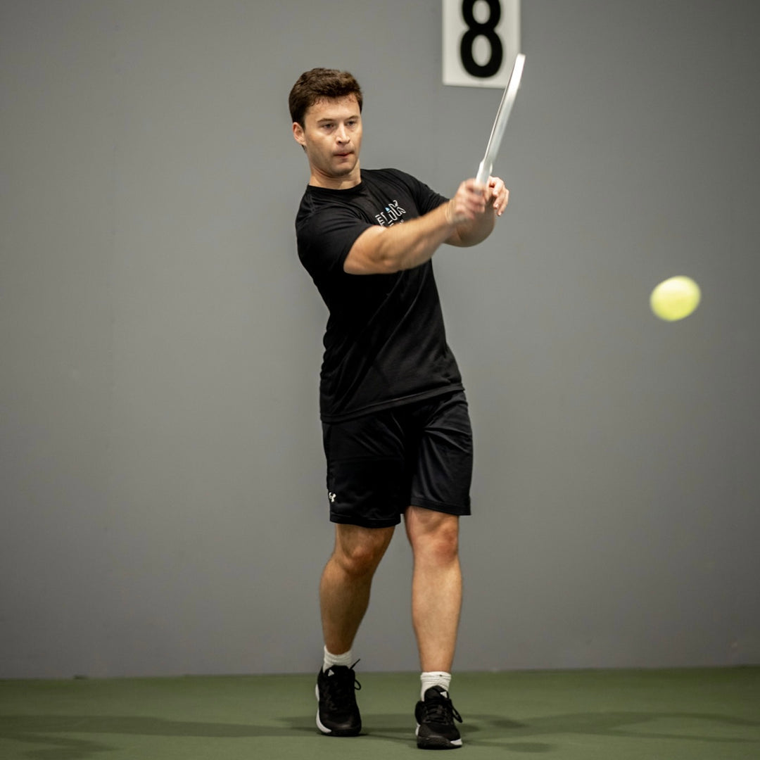 Man playing tennis with a racket and ball on a gray background