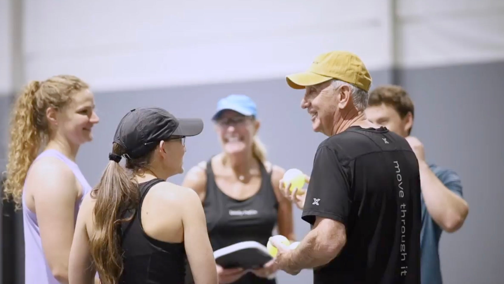 Group of people, including a coach, interacting in an indoor setting.