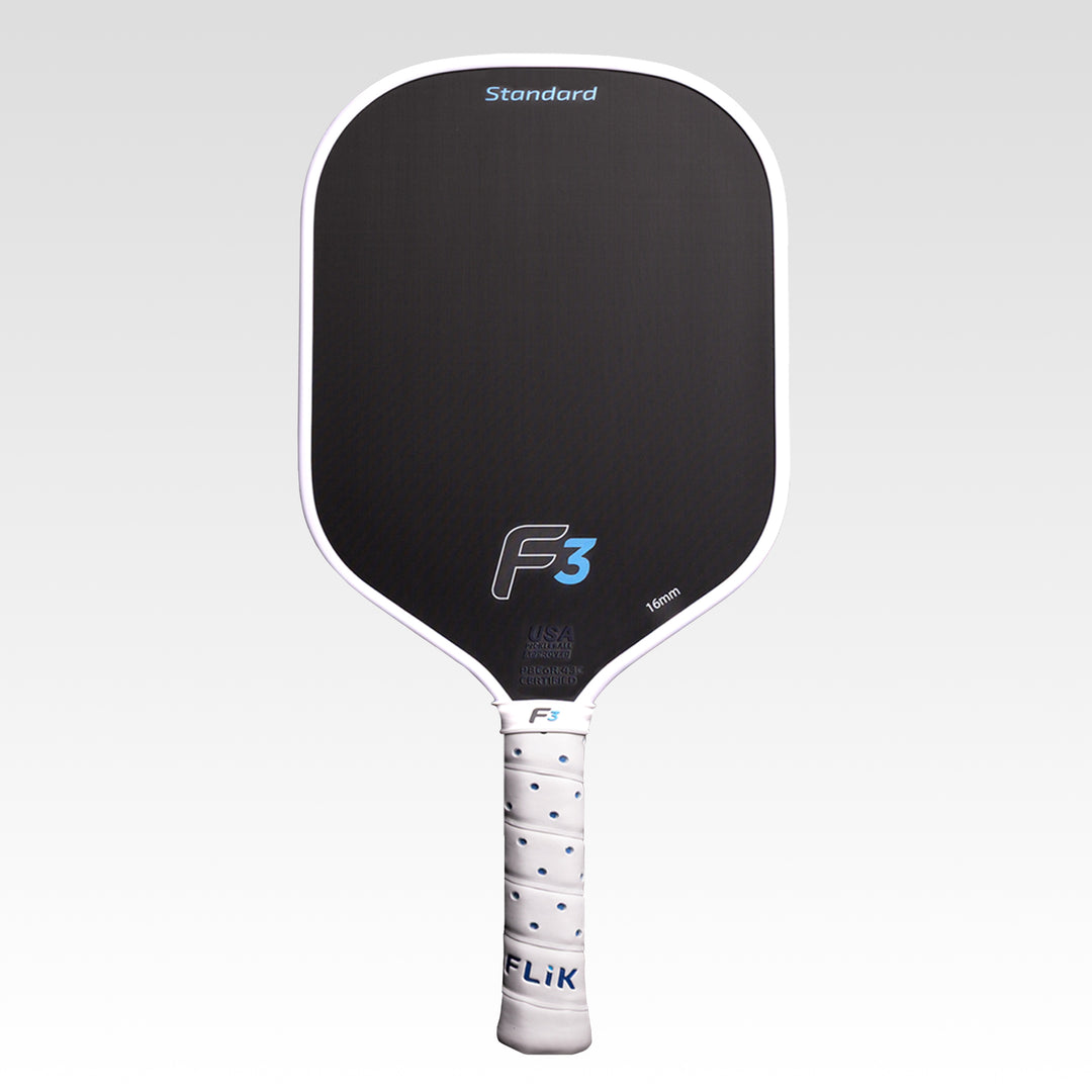 A FLiK pickleball paddle with a black paddle face, white border, white wrapped handle, and blue accents, shown against a light gray gradient background. The paddle features the &