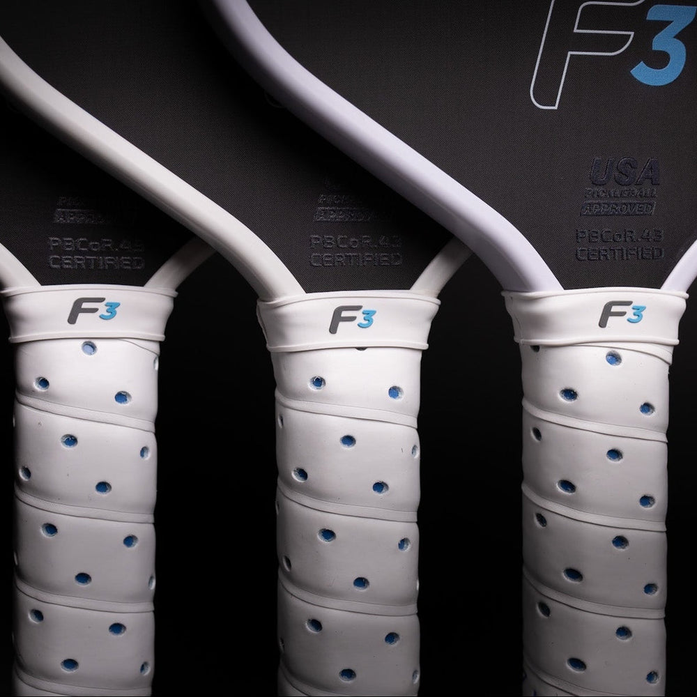 Three tennis rackets with white frames and white Paddle Replacement Grips featuring blue dots, arranged vertically against a dark background. The racket heads are dark gray/black with the F3 logo in white and blue, and 'USA' and '16mm' text visible.