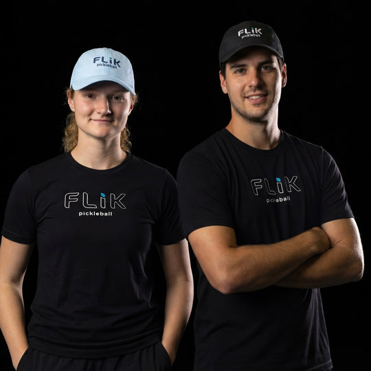 Two people wearing black Flik pickleball shirts and hats on a black background