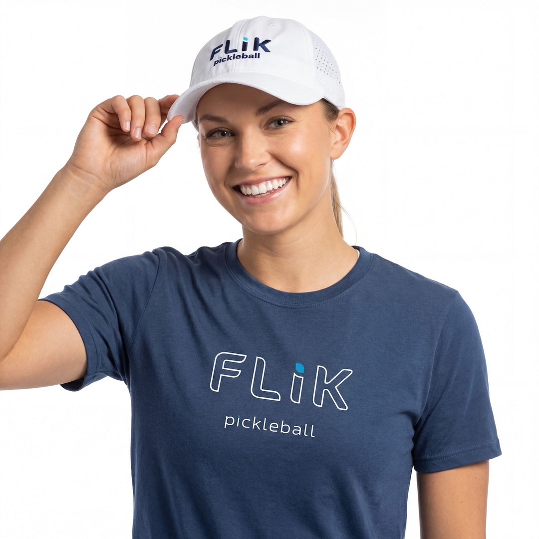 Woman wearing a blue 'Flik pickleball' t-shirt and white cap on a white background