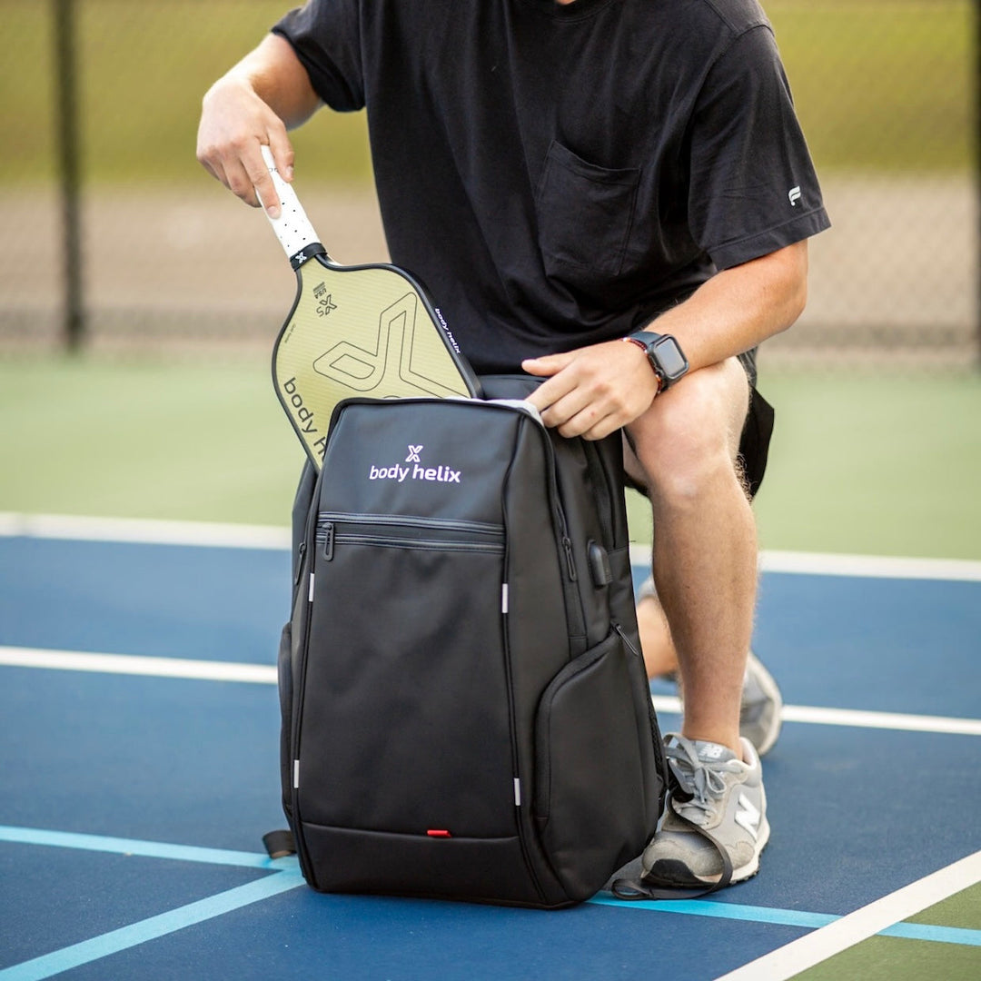 man pulling a body helix x5 pickleball paddle for spin out of his body helix backpack