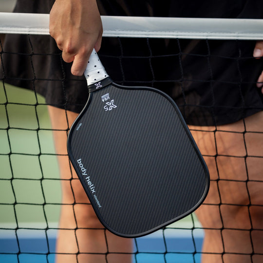 body helix X5 Black kevlar pickleball paddle held by a person on a pickleball ourt