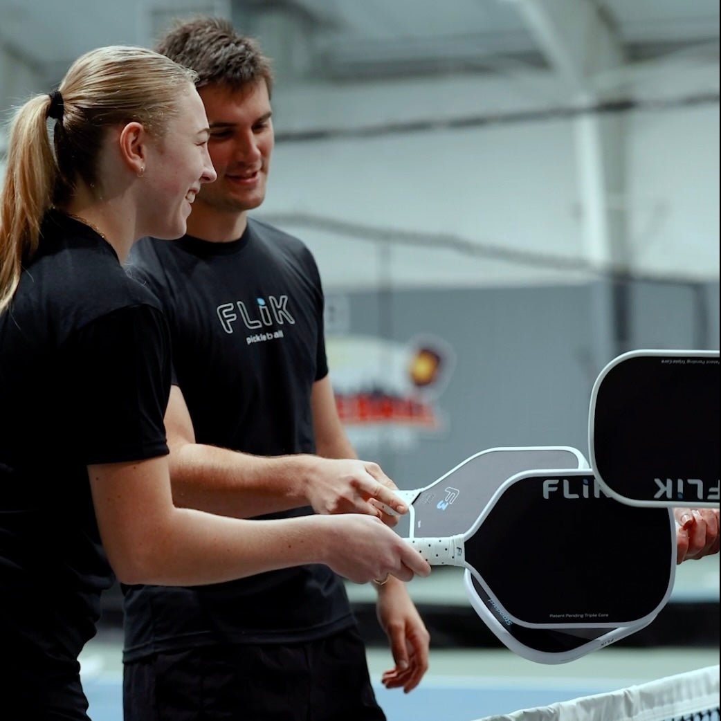 Two people holding Flik paddle rackets in an indoor setting