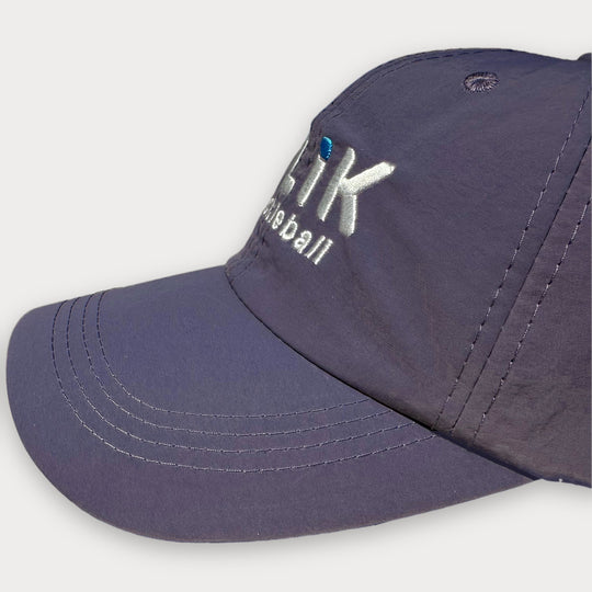 A close-up shot of a purple baseball cap with white embroidered text reading &